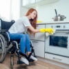 Mobility Young Womanin Wheelchair Cleaning Kitchen
