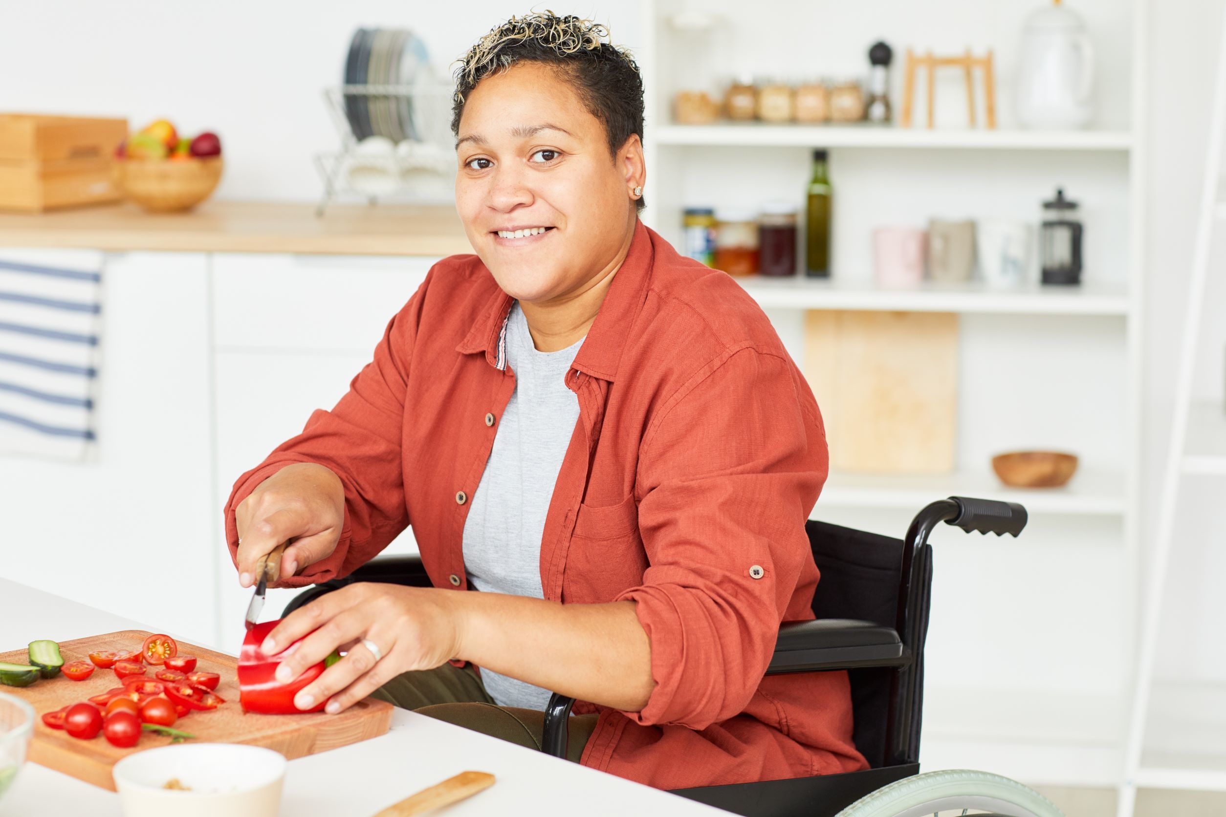 Woman Seated in Wheelchair Chopping Red Peppers Woman Seated in Wheelchair Chopping Red Peppers